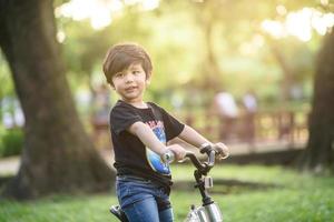 bangkok thailand - oktober 09, 2016 glücklicher fröhlicher kindjunge, der fahrrad im park in der natur fährt foto