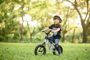 bangkok thailand - oktober 09, 2016 glücklicher fröhlicher kindjunge, der fahrrad im park in der natur fährt foto