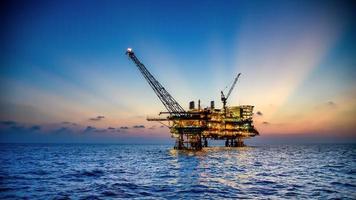 Offshore-Öl- und Bohrplattform bei Sonnenuntergang oder Sonnenaufgang. Aufbau des Produktionsprozesses im Meer. Macht Energie der Welt. foto