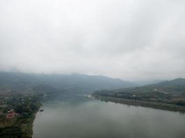 Die Bergkette ist nach dem Regen in der Nähe des großen Flusses von Wolken bedeckt. foto