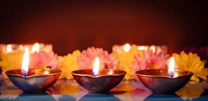Frohes Diwali. traditionelle symbole des indischen lichtfestes. brennende diya-öllampen und blumen auf rotem hintergrund. foto