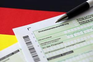 deutsches einkommensteuererklärungsformular mit stift auf flagge aus nächster nähe. das konzept der steuerberichterstattung in deutschland foto