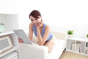glückliche Frau mit Tablet-PC auf Sofa foto
