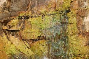 Wasserfall zwischen Steinen und Bäumen. Nahaufnahme von Felsbrocken im Wasser. riesige Steine im grünen Moos. schöne Landschaft mit schnellem Wasserfall mit kleinen Whirlpools foto