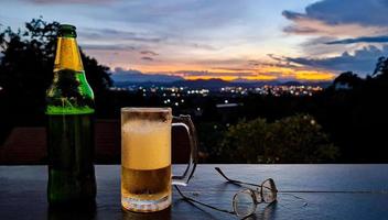 Bier mit der Städtelandschaft bei Sonnenuntergang foto