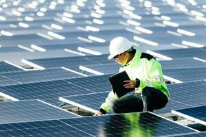 Nahaufnahme eines männlichen Elektrikers mit weißem Schutzhelm, der auf einer Leiter steht und ein Photovoltaik-Solarpanel unter einem wunderschönen blauen Himmel montiert. Konzept alternativer Energiequellen. foto