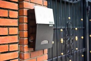 Briefkasten aus Metall an der Ziegelwand und weiße Adresstafel, selektiver Fokus foto