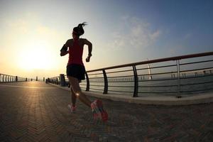 junger Fitnessfrauenläufer, der am Meer läuft foto