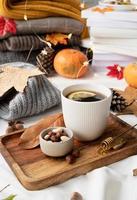 gemütliche Herbstkomposition, Pulloverwetter. heißer tee mit zitrone und nüssen auf holztablett, umgeben von herbstblättern und pullovern foto