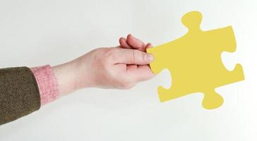 männliche hand, die gelbes puzzleteil hält foto