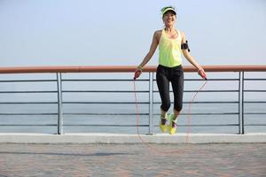 junge Fitnessfrau springendes Seil am Meer