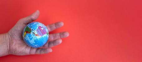 Globus in der Hand auf Rot und Papierhintergrund mit Platz für Text. foto