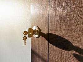 Hausschlüssel mit Hausschlüsselring im Schlüsselloch an der Holztür foto