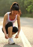 junge Fitnessfrau, die Schnürsenkel auf Straße bindet