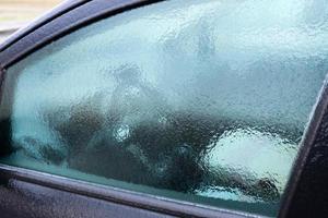 Das Autofenster ist mit Eis bedeckt, am frühen Morgen im Winter. foto