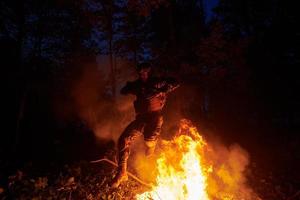 Soldat in Aktion bei Nacht beim Springen über Feuer foto