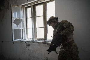 Soldat in Aktion in der Nähe des Fensterwechselmagazins und in Deckung gehen foto