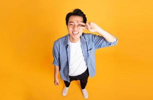 Bild des asiatischen Mannes, der auf einem gelben Hintergrund aufwirft foto