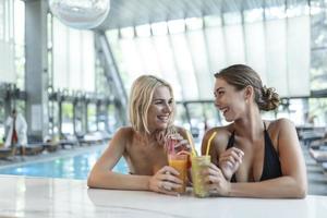 zwei attraktive junge frauen, die schwimmerbecken und cocktails genießen. Paar trinkt Mojito in der Poolbar foto