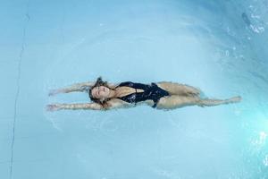 schöne glückliche frau mit sexy fittem körper, der sich entspannt und im schwimmbad im spa-hotel schwimmt. Sommerferien Urlaub. gesunder Lebensstil. Wellness, Schönheit, Gesundheitskonzept. Erholung foto