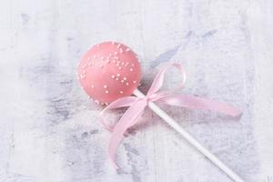 ein rosa Cake Pop auf einem strukturierten Hintergrund foto