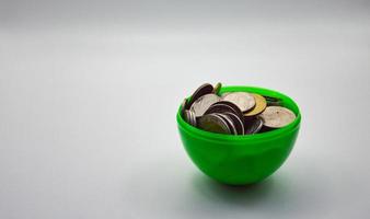Stapel von Münzen in grüner Tasse auf weißem Hintergrund Konzept Sparkonto Sparkasse Finanzgeschäft foto