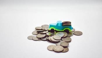 Ein blaugrüner Lastwagen mit Münzen klettert auf einem Stapel Münzen auf weißem Hintergrund. foto