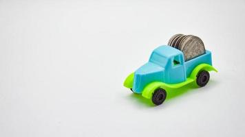 Silbermünzen, die auf einem blaugrünen Lastwagen gestapelt sind. weißem Hintergrund Konzept Autoversicherung Finanzgeschäft foto