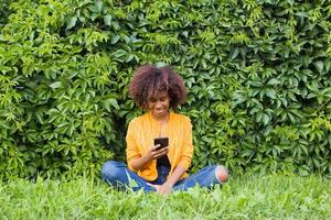 die glückliche afroamerikanerin auf der straße, die am telefon spricht foto