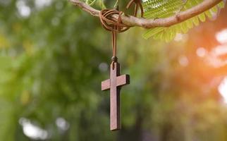 Holzkreuz, das an Baumzweigen hängt, weicher und selektiver Fokus, natürlicher Bokeh-Baumhintergrund, Konzept für Hoffnung, Liebe, Vergebung und Glauben an Jesus auf der ganzen Welt. foto