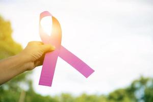 Rosafarbenes Papierband, das weibliche Teenager in den Händen hält, um alle Menschen auf der ganzen Welt zu zeigen und aufzurufen, die Brustkrebskampagne der Frau zu unterstützen und daran teilzunehmen, weicher und selektiver Fokus. foto