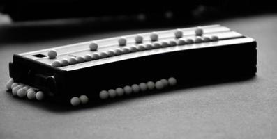 weiße Plastikkugelkugeln aus Airsoft-Pistole oder Bb-Pistole auf dunklem Boden weicher und selektiver Fokus auf weiße Pellets. foto