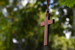 Holzkreuz, das an Baumzweigen hängt, weicher und selektiver Fokus, natürlicher Bokeh-Baumhintergrund, Konzept für Hoffnung, Liebe, Vergebung und Glauben an Jesus auf der ganzen Welt. foto