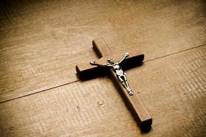 Nahaufnahme Holzkreuz, das eine Metallstatue des gekreuzigten Jesus hat, befindet sich auf einem Holztisch in einer örtlichen Kirche, weicher und selektiver Fokus. foto