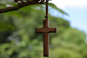 Holzkreuz, das an Baumzweigen hängt, weicher und selektiver Fokus, natürlicher Bokeh-Baumhintergrund, Konzept für Hoffnung, Liebe, Vergebung und Glauben an Jesus auf der ganzen Welt. foto