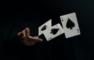 Pik-Ass-Spielkarte. Spieler oder Zauberer schnipsen und schwebende Pokerkarten von Hand. Vorderansicht. Nahaufnahme und dunkler Ton foto