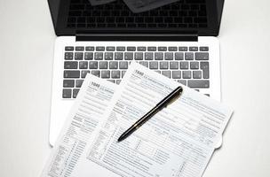 Schreibtisch mit Steuerformularen, Laptop und Stift, Hintergrund des Geschäftskonzepts foto