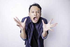 ein unzufriedener junger asiatischer mann sieht verärgert aus und trägt ein blaues marinehemd mit gereizten gesichtsausdrücken foto