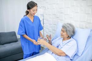 asiatische krankenschwestern geben älteren patienten im aufwachraum im krankenhaus-, gesundheits- und medizinkonzept medikamente. foto