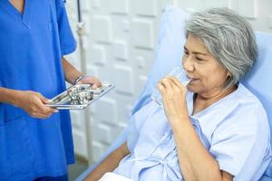 asiatische krankenschwestern geben älteren patienten im aufwachraum im krankenhaus-, gesundheits- und medizinkonzept medikamente.