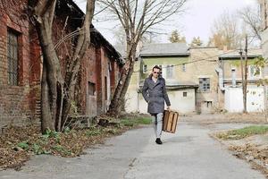 voller Länge eines Mannes mit Koffer, der durch eine leere Straße geht. foto