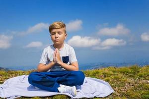 Zen wie ein Kind in Namaste-Pose, das auf dem Berggipfel meditiert. foto