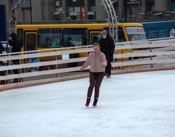 Die Leute haben Spaß beim Schlittschuhlaufen auf einer öffentlichen Eisbahn, die von der Gemeinde in den Straßen der Stadt während der Weihnachtszeit gebaut wurde foto