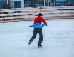 Die Leute haben Spaß beim Schlittschuhlaufen auf einer öffentlichen Eisbahn, die von der Gemeinde in den Straßen der Stadt während der Weihnachtszeit gebaut wurde foto