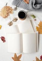 weißes leeres buch mit herbstblättern und tasse heißem tee auf altem tisch, mockup-design foto