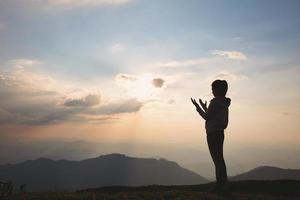 Silhouette einer Frau mit erhobenen Händen im Sonnenuntergang Konzept für Religion, Anbetung, Gebet und Lobpreis, religiöse Konzepte foto