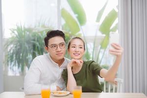 liebevolles paar, das morgens selfie macht. Orangensaft im Haus trinken foto