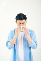 junger asiatischer mann, der niest, nachdem er eine allergie oder ein grippevirus bekommen hat, und mit seidenpapier in der medizinischen klinik auf die nase wischt, nachdem er eine coronavirus-codisease für ein ungesundes lebensstilkonzept bekommen hat foto