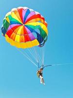 Mädchen Parascending am Fallschirm im blauen Himmel foto