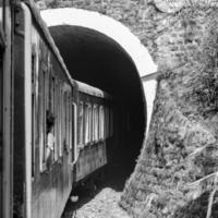 spielzeugeisenbahn, die sich am berghang bewegt, schöne aussicht, eine seite des berges, eine seite des tals, die auf der eisenbahn zum hügel fährt, inmitten grüner naturwälder. spielzeugeisenbahn von kalka nach shimla in indien-schwarz und weiß foto